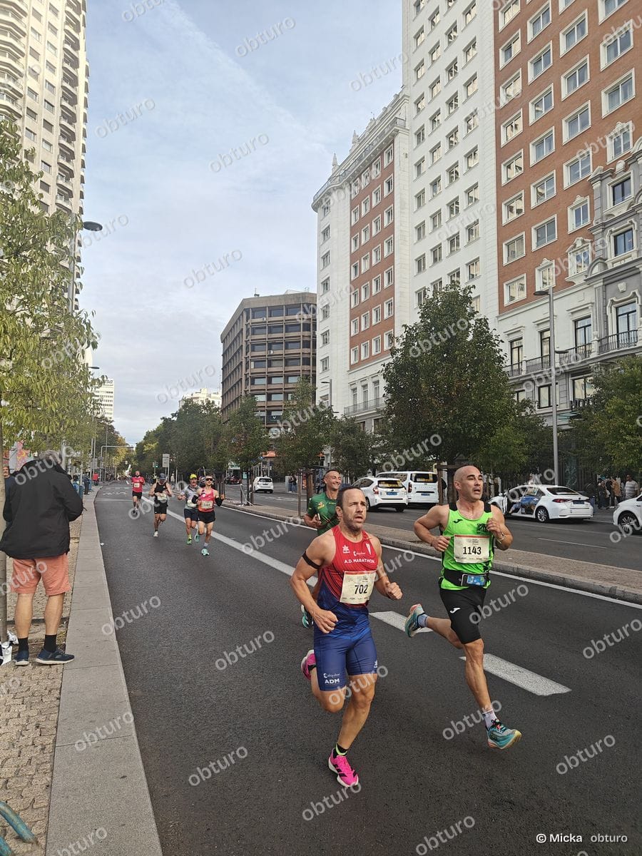Plusieurs participants s'élancent dans une rue urbaine lors d'une course à pied sous un ciel légèrement nuageux.